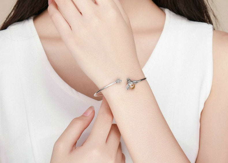 Woman wearing heart-shaped silver bracelet, part of the Bee Bangle story.