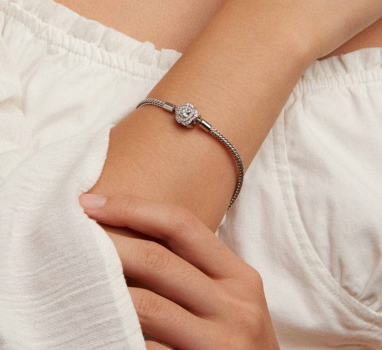 A woman in a white shirt and silver bracelet, showcasing a handmade snake chain bracelet with a variety clasp.